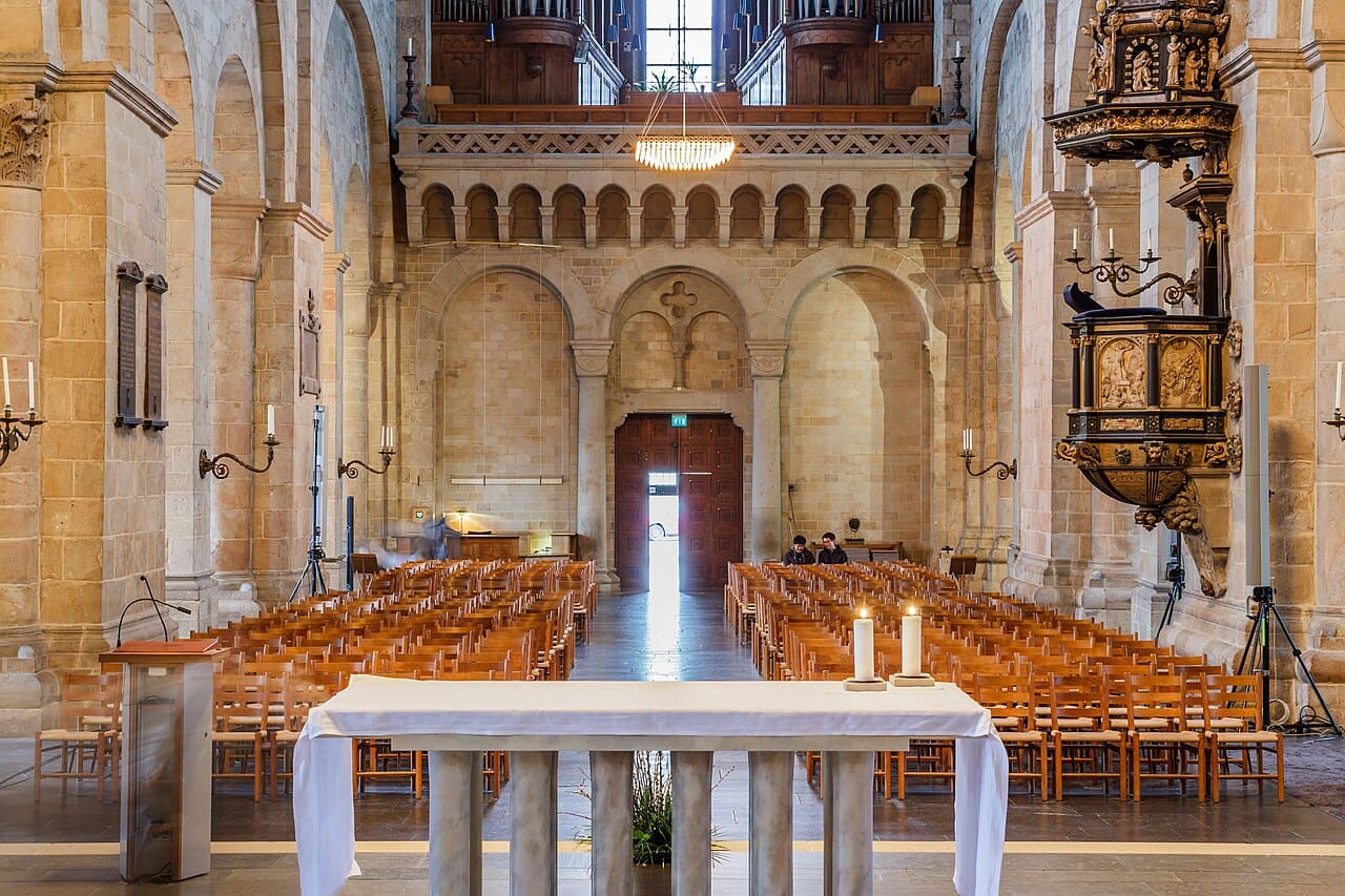Mittskeppet i Lunds domkyrka med altare, tända ljus och stolsrader